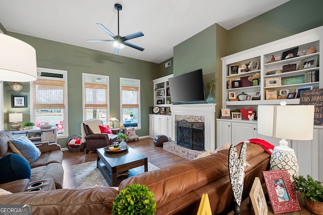 living room featuring wood-type flooring, a brick fireplace, and plenty of natural light