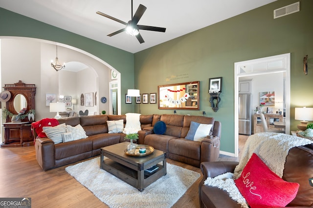 living room with wood-type flooring and ceiling fan with notable chandelier