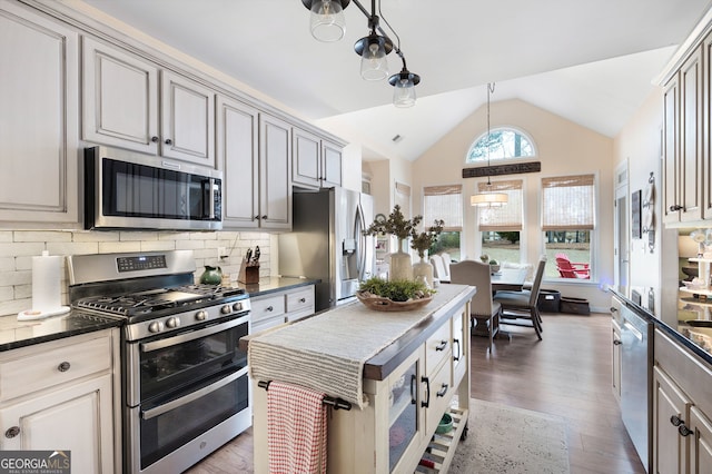 kitchen with lofted ceiling, appliances with stainless steel finishes, hanging light fixtures, tasteful backsplash, and dark hardwood / wood-style flooring