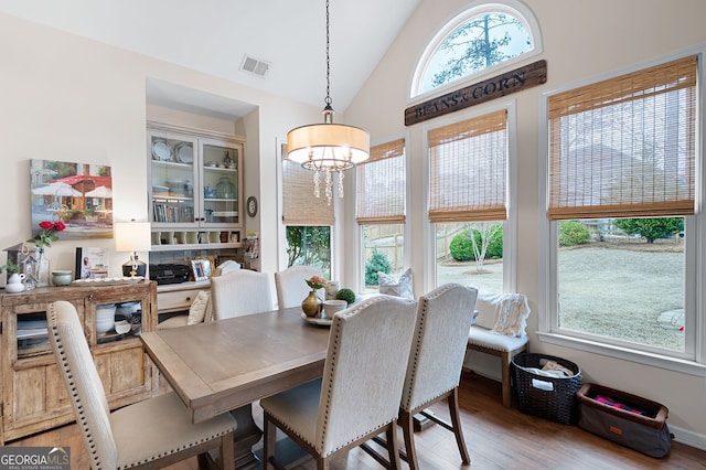 dining room with an inviting chandelier, vaulted ceiling, and light wood-type flooring