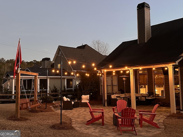 back house at dusk featuring an outdoor living space with a fire pit and a patio area