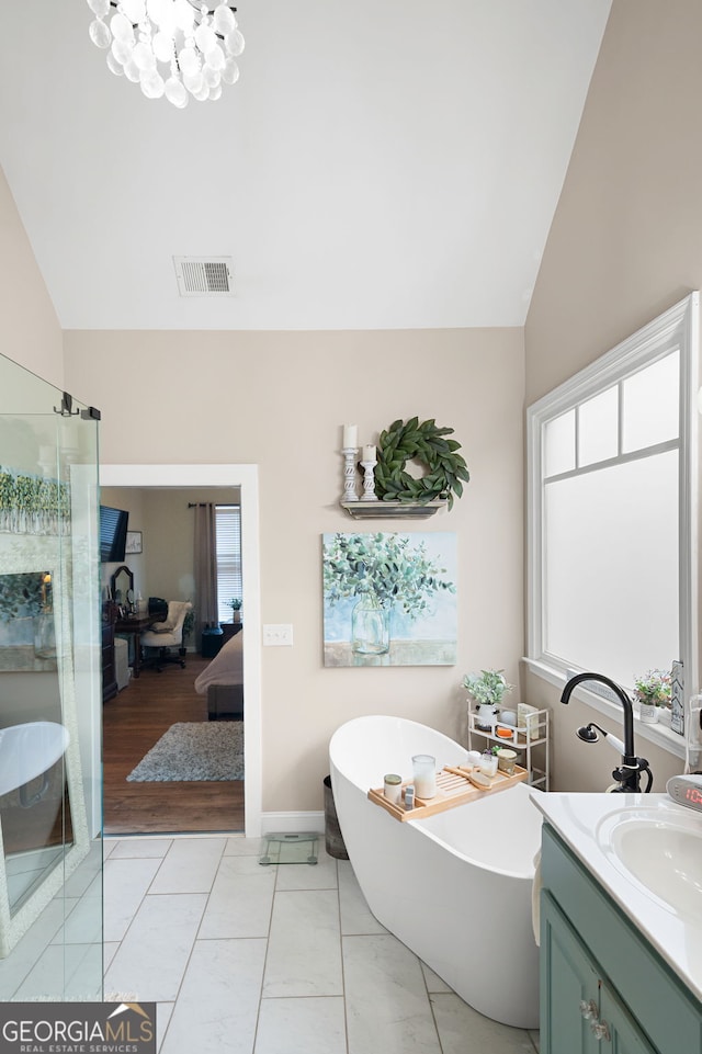 bathroom with lofted ceiling, vanity, a wealth of natural light, and a washtub