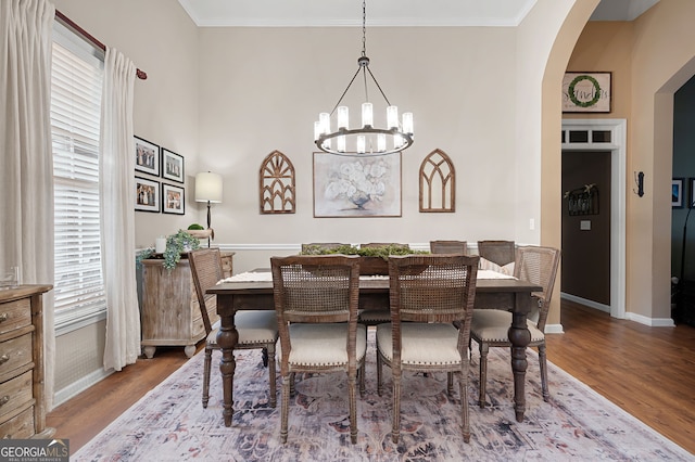 dining room with ornamental molding, wood-type flooring, and a notable chandelier