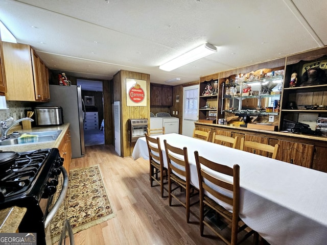 kitchen with gas stove, sink, heating unit, washer and dryer, and light hardwood / wood-style floors