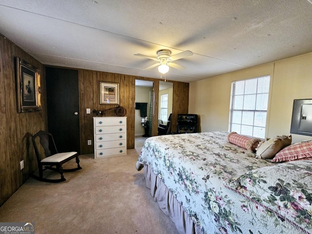 carpeted bedroom with ceiling fan, a textured ceiling, and wood walls