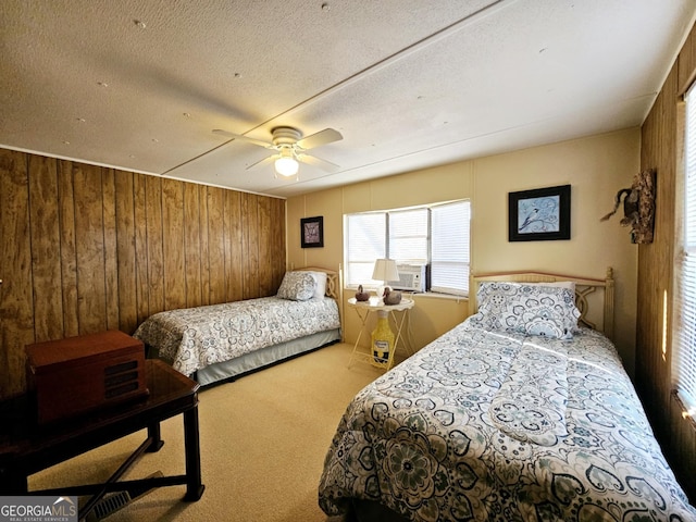 bedroom with wood walls, a textured ceiling, carpet floors, cooling unit, and ceiling fan