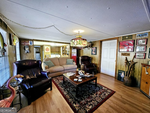 living room with wood-type flooring, wooden walls, and a textured ceiling