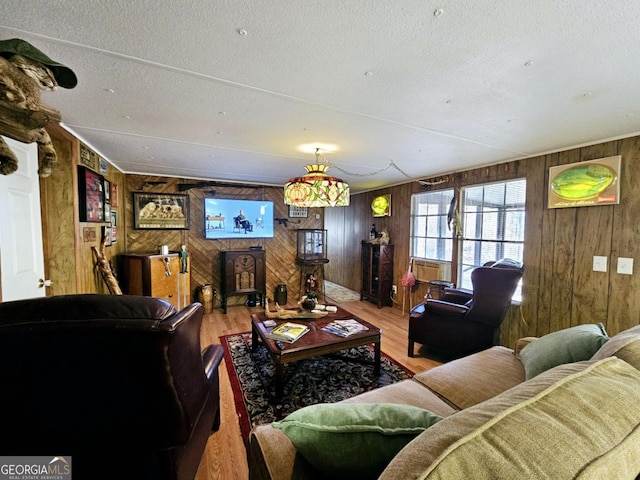 living room with hardwood / wood-style floors, a textured ceiling, and wooden walls