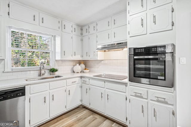 kitchen featuring stainless steel appliances, white cabinetry, sink, and backsplash