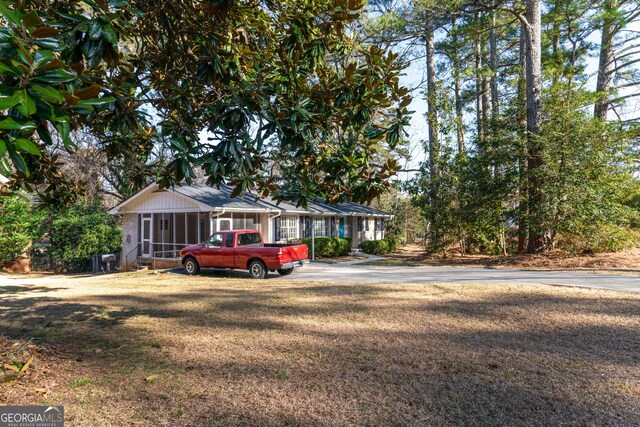 ranch-style house featuring a sunroom and a front lawn