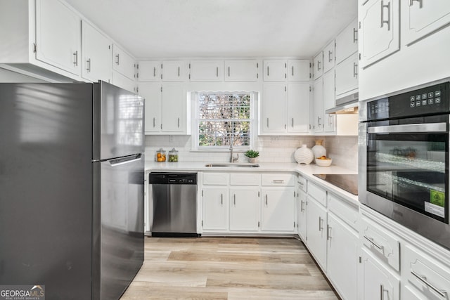 kitchen with sink, light hardwood / wood-style flooring, white cabinets, stainless steel appliances, and backsplash