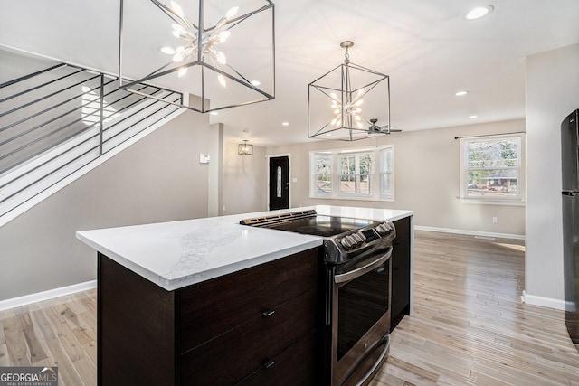 kitchen featuring stainless steel electric stove, a center island, a notable chandelier, dark brown cabinetry, and light hardwood / wood-style flooring