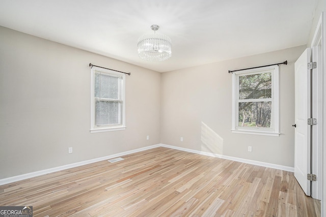 spare room with light hardwood / wood-style floors and a chandelier