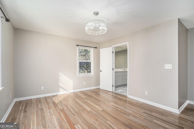 interior space with ensuite bathroom, a notable chandelier, and light hardwood / wood-style flooring