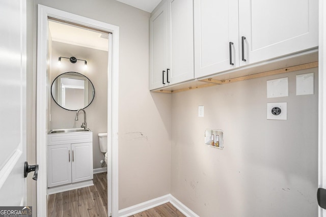 laundry area featuring sink, cabinets, washer hookup, hookup for an electric dryer, and light hardwood / wood-style flooring