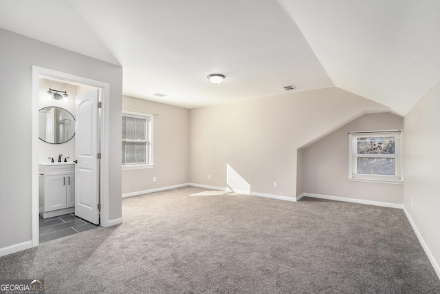 bonus room with sink, vaulted ceiling, and dark colored carpet