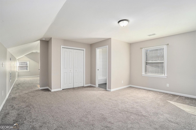 unfurnished bedroom featuring light colored carpet, lofted ceiling, and a closet