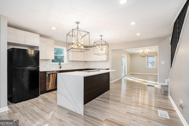 kitchen featuring sink, hanging light fixtures, black refrigerator, dishwasher, and a kitchen island