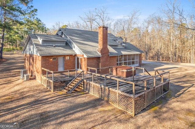 back of property featuring central AC unit, a hot tub, and a deck