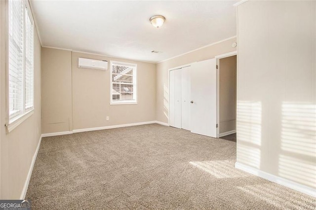 unfurnished bedroom with crown molding, carpet flooring, a wall mounted AC, and a closet