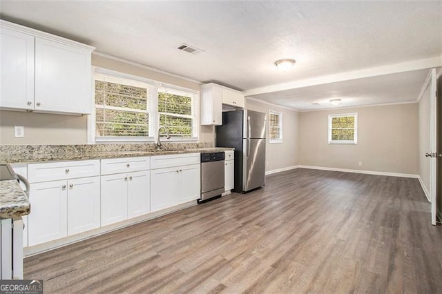 kitchen with light stone counters, stainless steel appliances, light hardwood / wood-style floors, and white cabinets