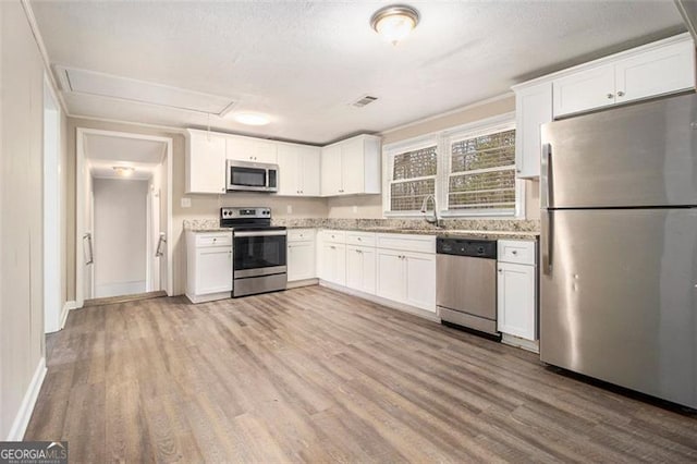 kitchen featuring stainless steel appliances, sink, white cabinets, and light wood-type flooring