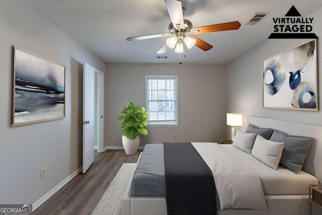 bedroom featuring dark hardwood / wood-style flooring, ceiling fan, and a textured ceiling