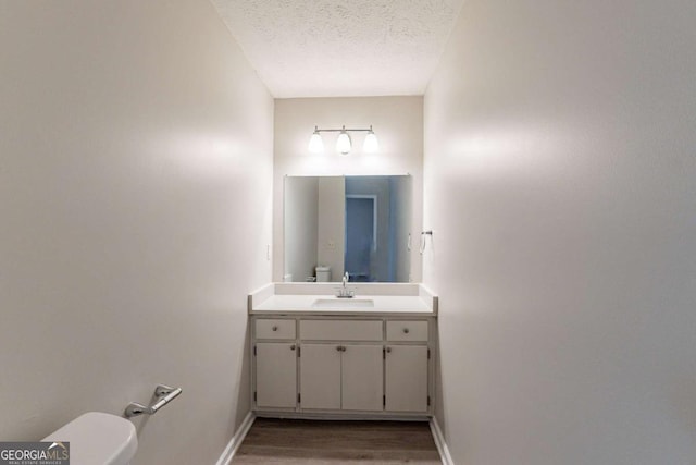 bathroom featuring vanity, hardwood / wood-style flooring, toilet, and a textured ceiling