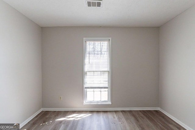 spare room featuring dark hardwood / wood-style flooring, plenty of natural light, and a textured ceiling