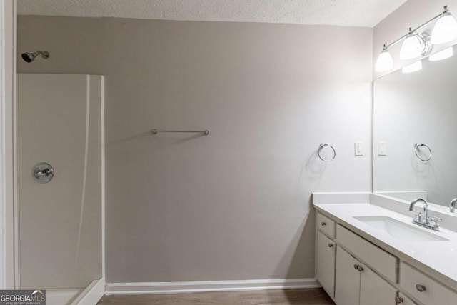 bathroom with walk in shower, vanity, hardwood / wood-style floors, and a textured ceiling