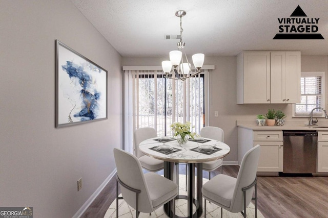 dining space featuring an inviting chandelier, sink, light hardwood / wood-style flooring, and a textured ceiling
