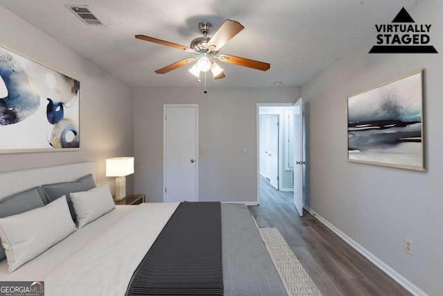 bedroom featuring ceiling fan, wood-type flooring, and a textured ceiling