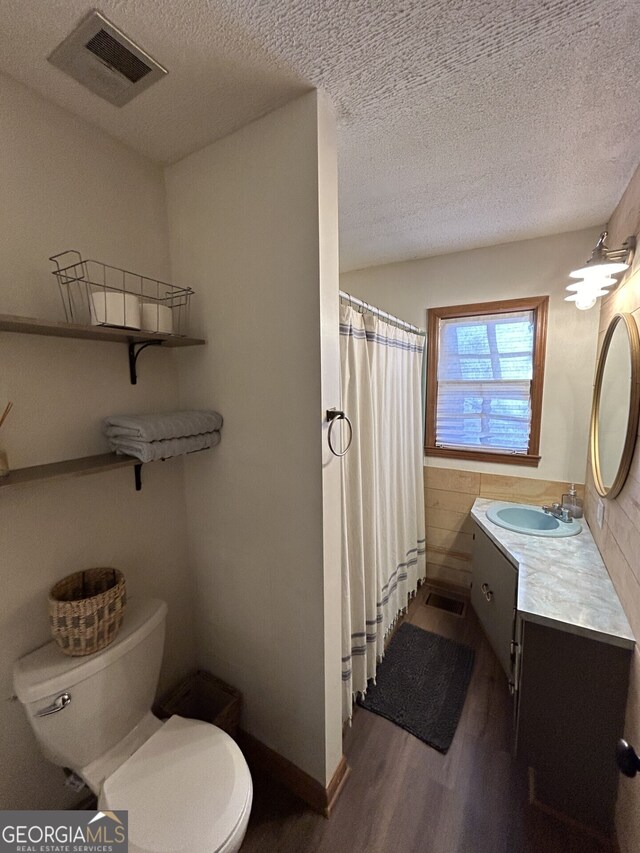 bathroom featuring hardwood / wood-style flooring, vanity, a textured ceiling, and toilet