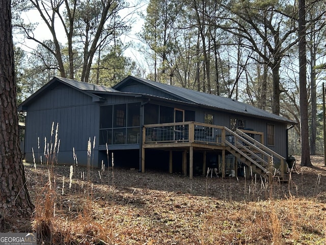 rear view of house with a wooden deck and a sunroom