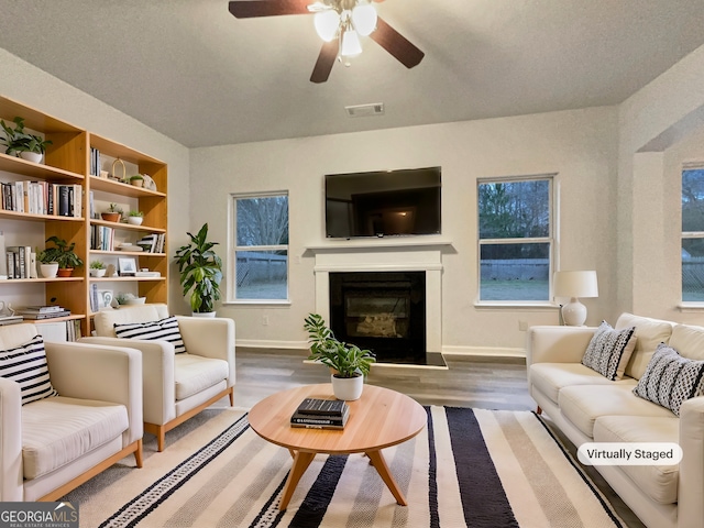 living room featuring dark wood-type flooring, ceiling fan, and built in shelves