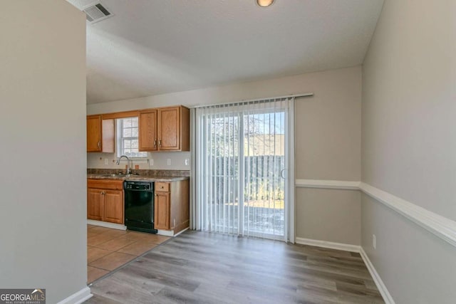 kitchen featuring light hardwood / wood-style floors, black dishwasher, and sink