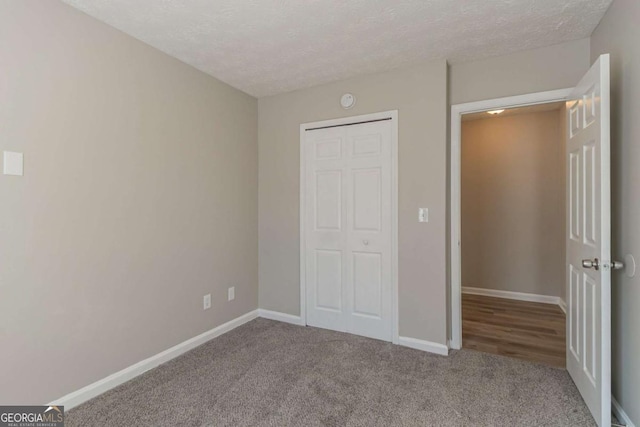 unfurnished bedroom featuring carpet floors, a textured ceiling, and a closet