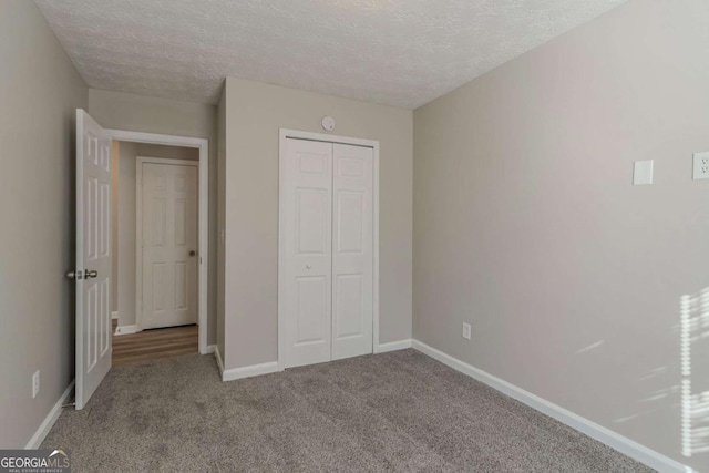 unfurnished bedroom featuring light colored carpet, a closet, and a textured ceiling