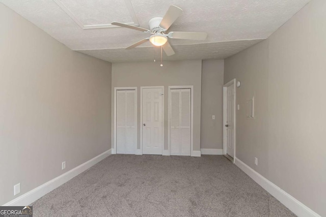 unfurnished bedroom with multiple closets, ceiling fan, carpet floors, and a textured ceiling