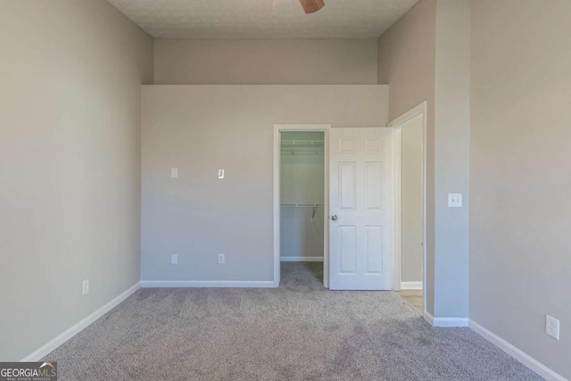 unfurnished bedroom featuring a walk in closet, light colored carpet, and a closet