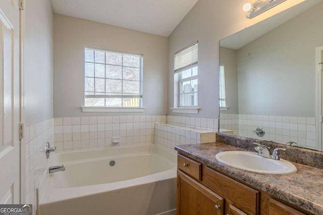 bathroom with a bathing tub, lofted ceiling, and vanity