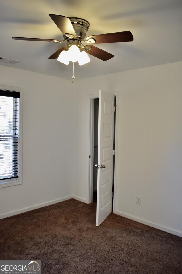 spare room with dark colored carpet and ceiling fan