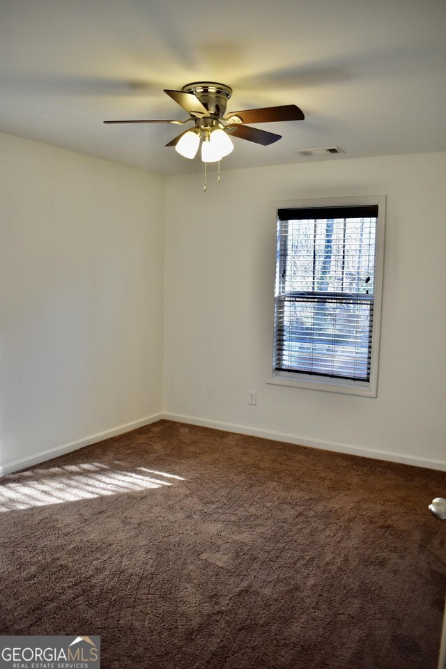 empty room featuring ceiling fan and carpet