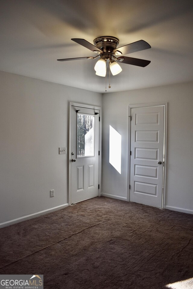 foyer entrance with ceiling fan and carpet flooring