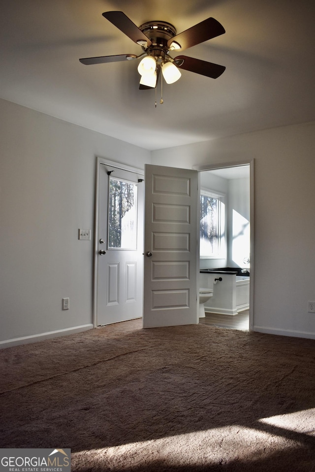 foyer entrance featuring ceiling fan and carpet