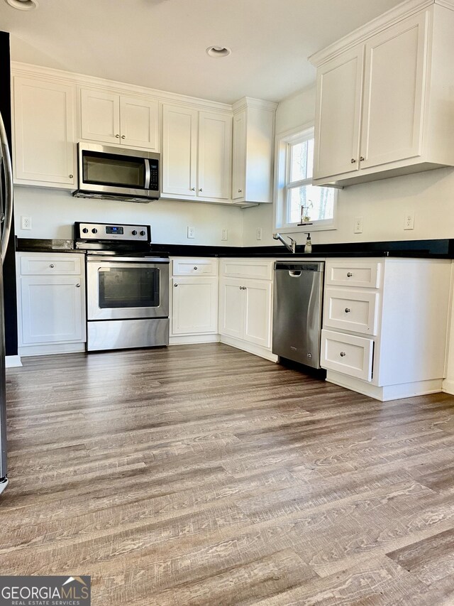 kitchen featuring stainless steel appliances, light wood-type flooring, and white cabinets