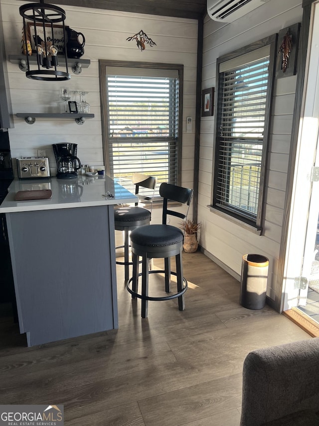 interior space with dark wood-type flooring, wood walls, and an AC wall unit