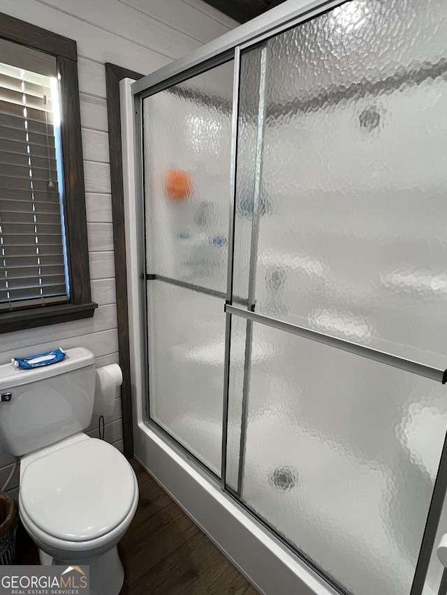 bathroom featuring an enclosed shower, hardwood / wood-style flooring, and wood walls