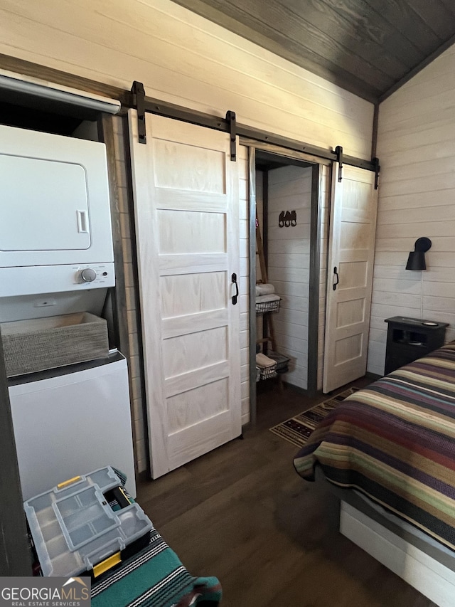 bedroom featuring a closet, a barn door, dark hardwood / wood-style floors, and wood walls