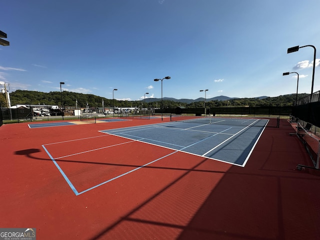 view of tennis court featuring basketball hoop and a mountain view